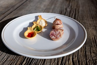 A Plate with Luganighe Sausage and with Species in Spoon Like Saffron and Parmesan Cheese and Rosemary on a Plate on a Wood Table with Sunlight in Lugano