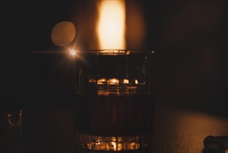 Image of a glass with a cocktail in a night bar against the background of a fiery heater. Restaurant concept