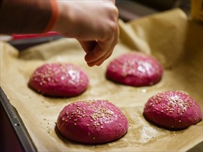 Beetroot burger buns Buns on a baking tray are sprinkled with sesame seeds