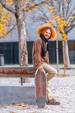 Vertical portrait of the side view of an alternative adult man with a skate in an urban park in autumn