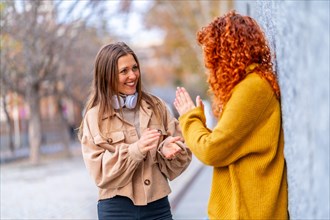 Two modern femalefFriends smiling and talking in the street