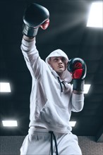 Brutal athlete boxing in the ring in a white hoodie covered with a hood. Mixed martial arts concept. High image quality