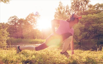 Young woman stretches after jogging. Sunny evening. Fitness concept.