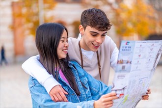 Multi-ethnic young friends looking at a city map visiting a city