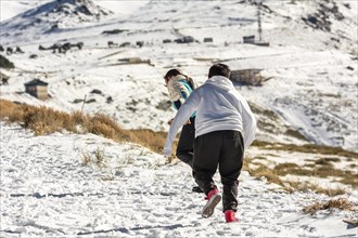 Latin mother and son running in the snow in Sierra Nevada Granada