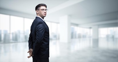 Portrait of a businessman in a suit. He is standing in the office of a skyscraper. Business concept.