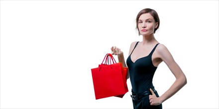 Beautiful young woman holding a craft red package in her hand. Shopaholics concept. Spenting. Gifts for the holidays. Black Friday. Shopping centers.