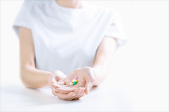 Woman in hospital clothes holds a set of pills in her palms. The concept of unstable psyche