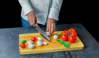 Professional chef cuts vegetables with a sharp knife from Damascus steel.
