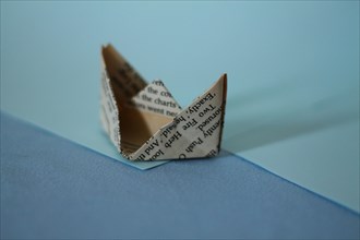 A paper boat in origami form against a contrasting blue background