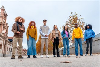 Frontal low angle view of friends of diverse ethnicity standing on an urban park