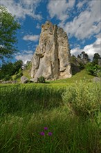 Striking limestone rock formation Burgstein with blue and white sky in the upper Altmuehltal surrounded by green vegetation