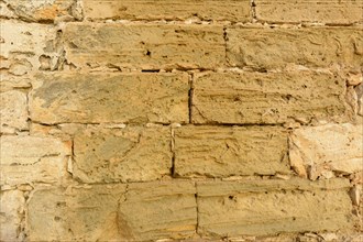Close-up of a textured stone wall with varying beige tones and rough surface