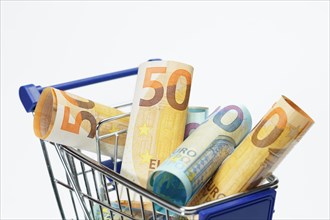 Shopping cart full of rolled up euro banknotes