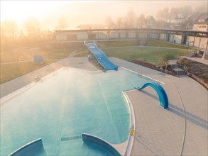 The slides set up in a swimming pool catch the first rays of sunshine of the day