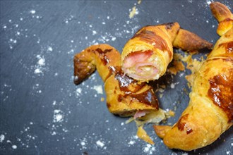 Sliced baked pastry with ham and cheese on a dark background