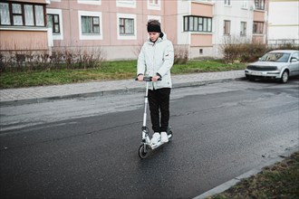 Young stylish guy rides an electric scooter around the city