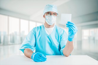 Portrait of a doctor holding a white sheet of paper in his hand. Medical concept.