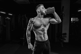 Portrait of an athlete drinking from a shaker in the gym. Bodybuilding and fitness concept.