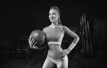 Charming blonde posing in the gym with a fitness ball. Front view. The concept of sports