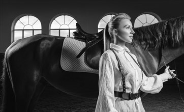 Portrait of a stylish woman hugging a thoroughbred horse. Love and care concept.