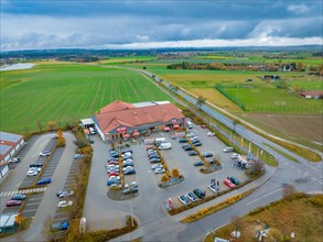 Aerial view of a shopping centre with a full car park next to fields
