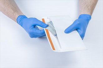 Image of hands in medical gloves holding an envelope with dollars. The concept of corruption in medicine.