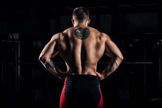 Huge weightlifter stands with his back to the camera and shows his huge back. Back view