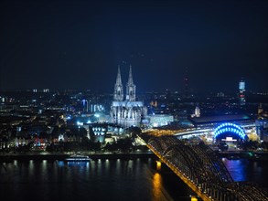 Aerial night view of St Peter Cathedral and Hohenzollern Bridge over river Rhine in Cologne