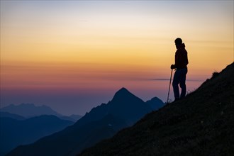 Mountaineer on mountain ridge with Rothorn peak in the background at blue hour