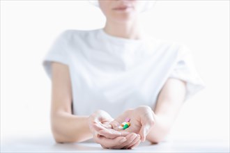 Woman in hospital clothes holds a set of pills in her palms. The concept of unstable psyche