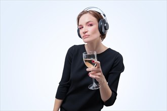 Portrait of a woman in professional headphones with a glass of wine in her hand. White background. Dj concept.