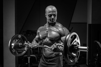 Professional weightlifter posing in the gym with a barbell in his hands. Classic bodybuilding.