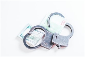 Packs of euros and hundred dollar bills are enclosed in handcuff bracelets. The concept of theft
