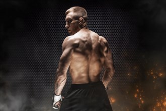 Kickboxer portrait on steel grid background. Back view. The concept of sports and mixed martial arts.