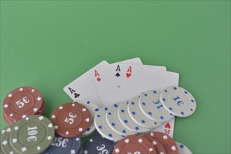 A hand of aces above neatly stacked poker chips on green felt
