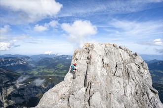 Female mountaineer climbing a via ferrata secured with a steel cable