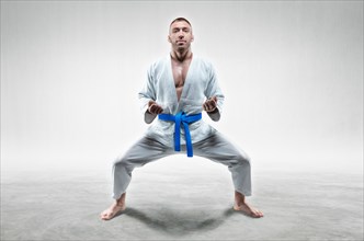 Athlete in a kimono with a blue belt stands in a fighting position. Concept of karate