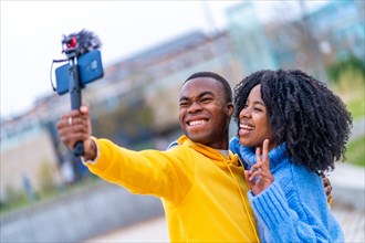 African young people smiling and gesturing victory while recording a video in the street