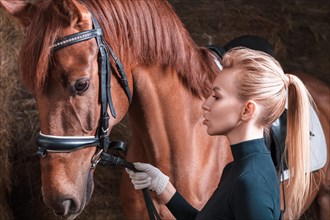 Stunning blonde posing with a thoroughbred horse. Ranch vacation concept.