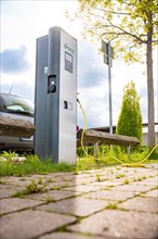 Electric vehicle charging station outside with surrounding nature and partly cloudy sky