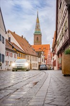 Deer E- Carsharing car in a street with cobblestones in front of a church