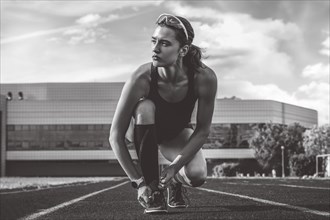Image of an athlete tying her shoelaces with spikes. Running concept.