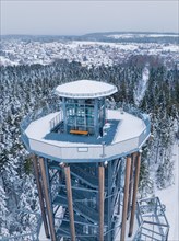 Snow surrounds a high viewing platform in the middle of a dense forest