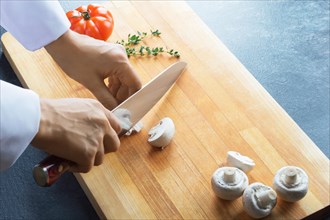 Professional chef woman slicing vegetables on a board. Side view