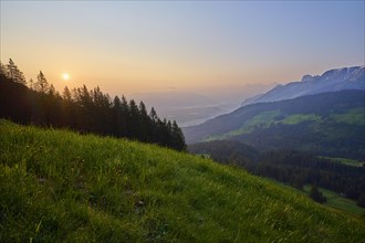 Sunrise over the valley with a view of green alpine meadows and forests