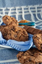 Delicious cookies and chocolate on a blue napkin over a woven texture