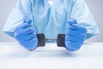 Hands of a doctor in handcuffs. The concept of corruption in medicine.