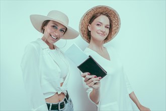 Portrait of two smiling women with passports and boarding passes in their hands. Travel concept.