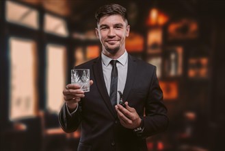 Portrait of an elegant man in a suit with a smoking pipe and a glass in a restaurant. Business concept.